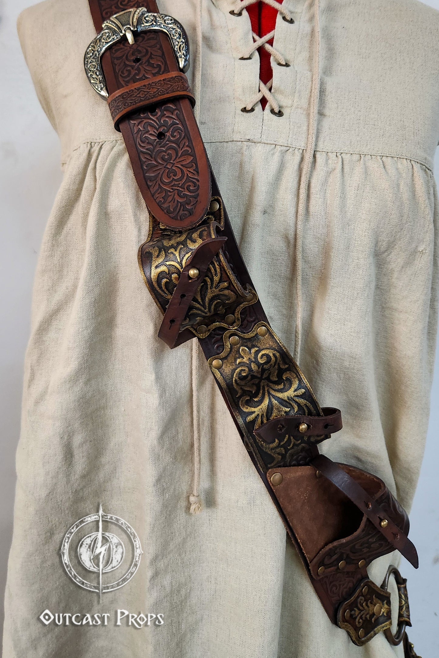 Decorative leather belt with intricate designs on a beige outfit. Pirate baldric for 4 flintlock pistols and a sword, inspired by Blackbeard, Anne Bonny, Captain Kidd and Pirates of the Caribbean. Ideal for LARP, Renfaire, renaissance fair, Pirate Weekend, cosplay, Halloween and Black Sails. Silver-engraved leather, handmade with vegetable-tanned leather. Premium pirate shoulder belt for Jack Sparrow costume, historical reenactment and fantasy events. High quality pirate accessory for themed outfits and pho