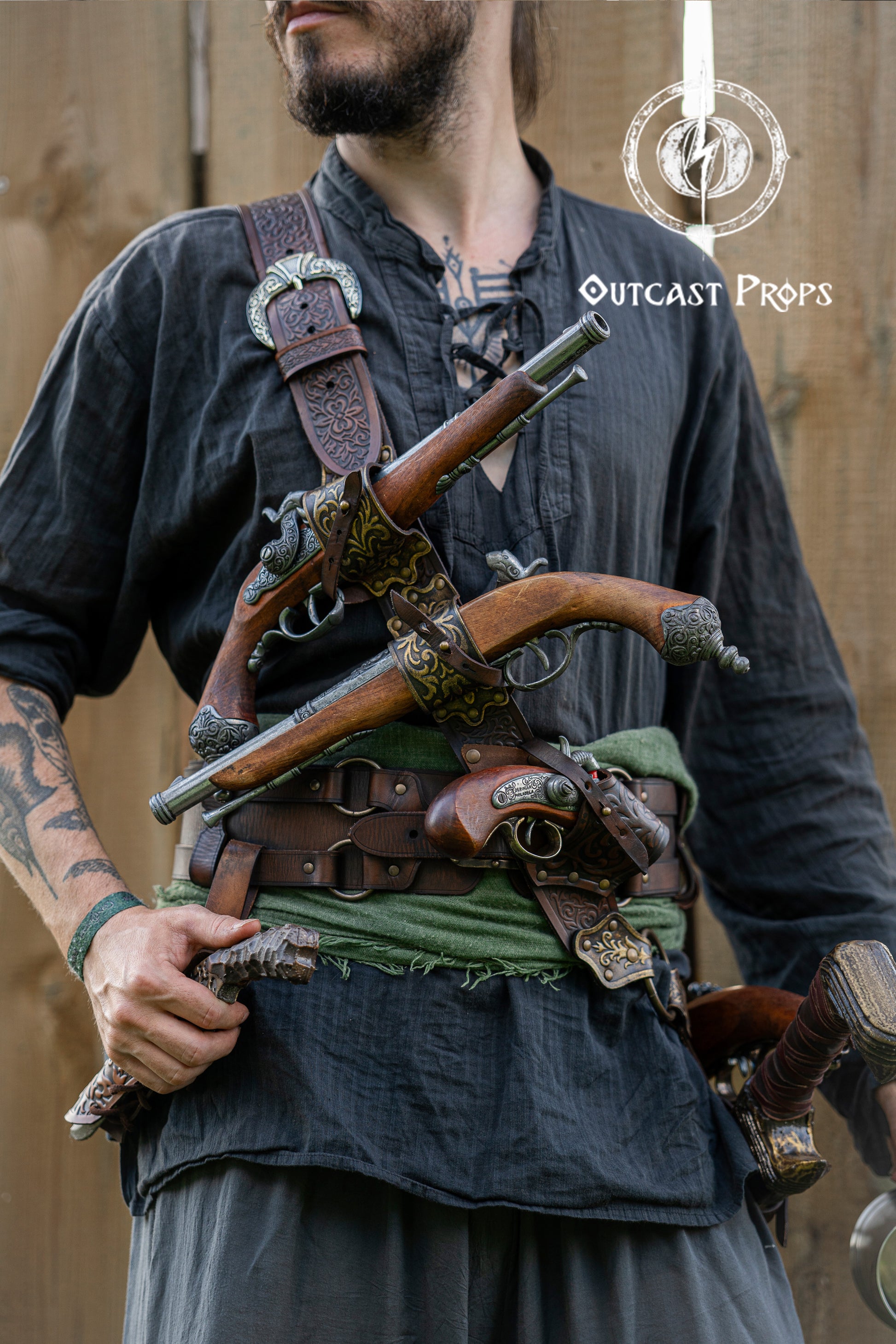 Close-up of a pirate baldric holding four flintlock pistols across the chest, crafted from engraved leather. Inspired by Pirates of the Caribbean, this premium belt is ideal for Jack Sparrow cosplay, LARP, renfaire and fantasy events. The leatherwork features silver details and historical styling. Perfect for pirate costumes based on Anne Bonny, Blackbeard or Captain Kidd. A high-quality fantasy accessory for reenactment and photoshoots.