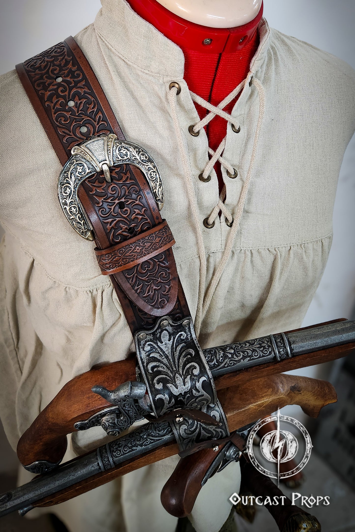 Decorative leather and metal weapon sheath on a mannequin wearing a historical outfit. Pirate baldric for 4 flintlock pistols and a sword, inspired by Blackbeard, Anne Bonny, Captain Kidd and Pirates of the Caribbean. Ideal for LARP, Renfaire, renaissance fair, Pirate Weekend, cosplay, Halloween and Black Sails. Silver-engraved leather, handmade with vegetable-tanned leather. Premium pirate shoulder belt for Jack Sparrow costume, historical reenactment and fantasy events. High quality pirate accessory for t