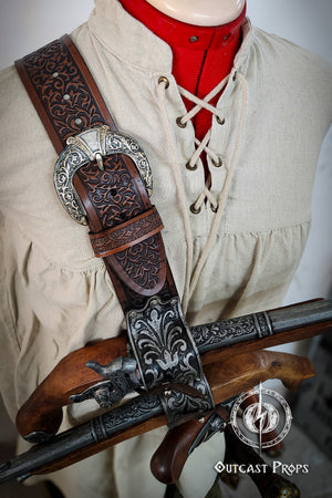 Decorative leather and metal weapon sheath on a mannequin wearing a historical outfit. Pirate baldric for 4 flintlock pistols and a sword, inspired by Blackbeard, Anne Bonny, Captain Kidd and Pirates of the Caribbean. Ideal for LARP, Renfaire, renaissance fair, Pirate Weekend, cosplay, Halloween and Black Sails. Silver-engraved leather, handmade with vegetable-tanned leather. Premium pirate shoulder belt for Jack Sparrow costume, historical reenactment and fantasy events. High quality pirate accessory for t