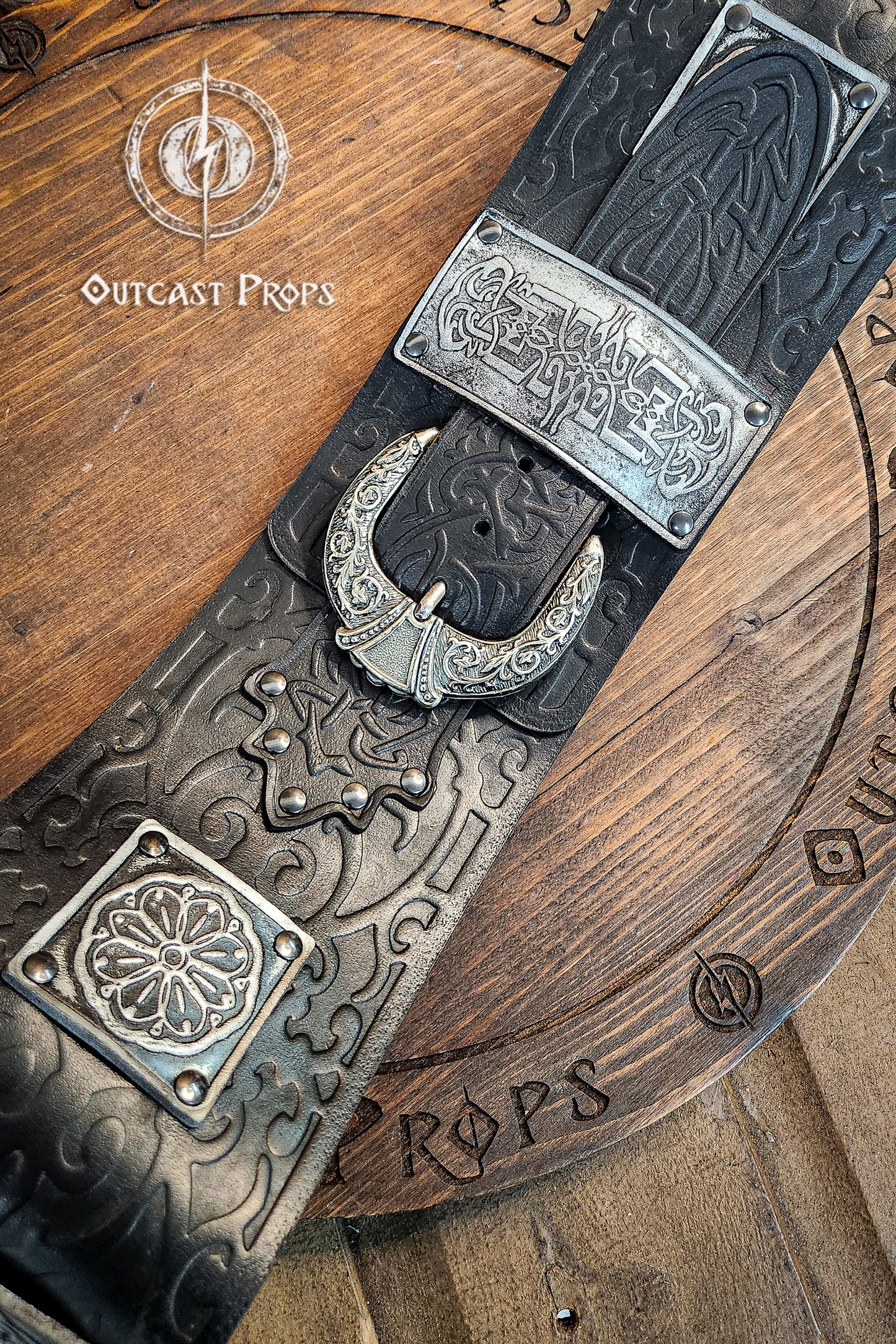 Detailed view of crescent-shaped silver buckle and engraved plates on black leather. This persian leather belt combines historical elegance and sturdy design. Crafted for LARP belt for costume and fantasy outfits.