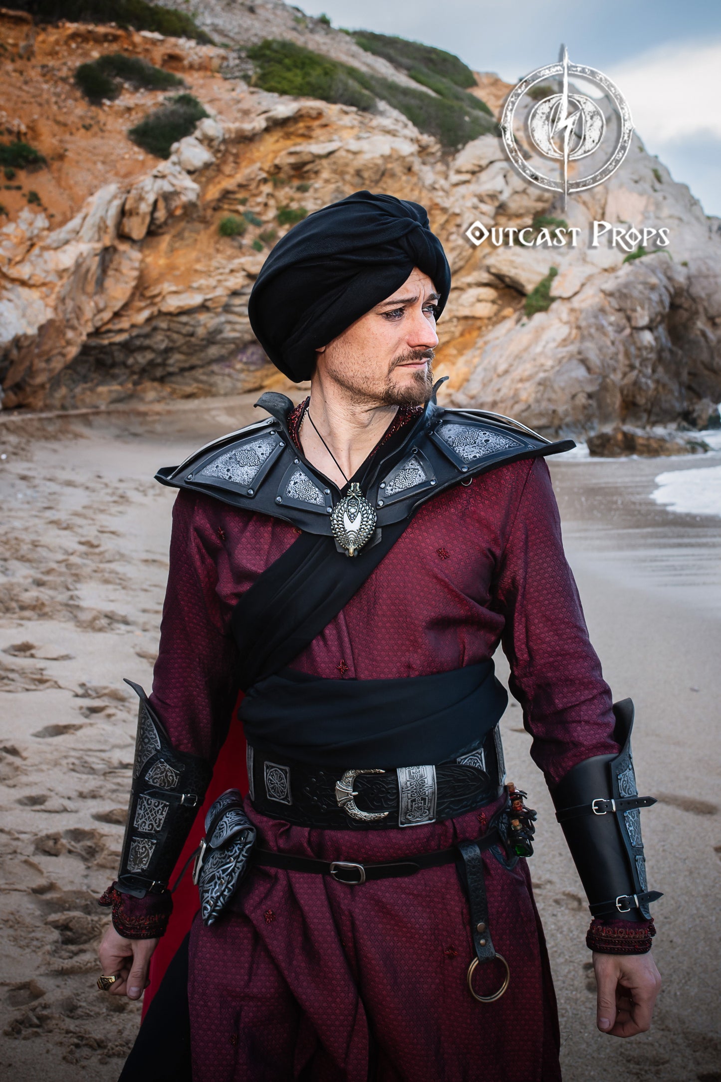 Man in medieval armor standing on a rocky beach . LARP character in Arabic-inspired costume wearing the wide leather belt with matching vambraces. The black leather belt stands out with its silver plates. Ideal image for keywords like black leather belt, larp belt, and belt for costume.