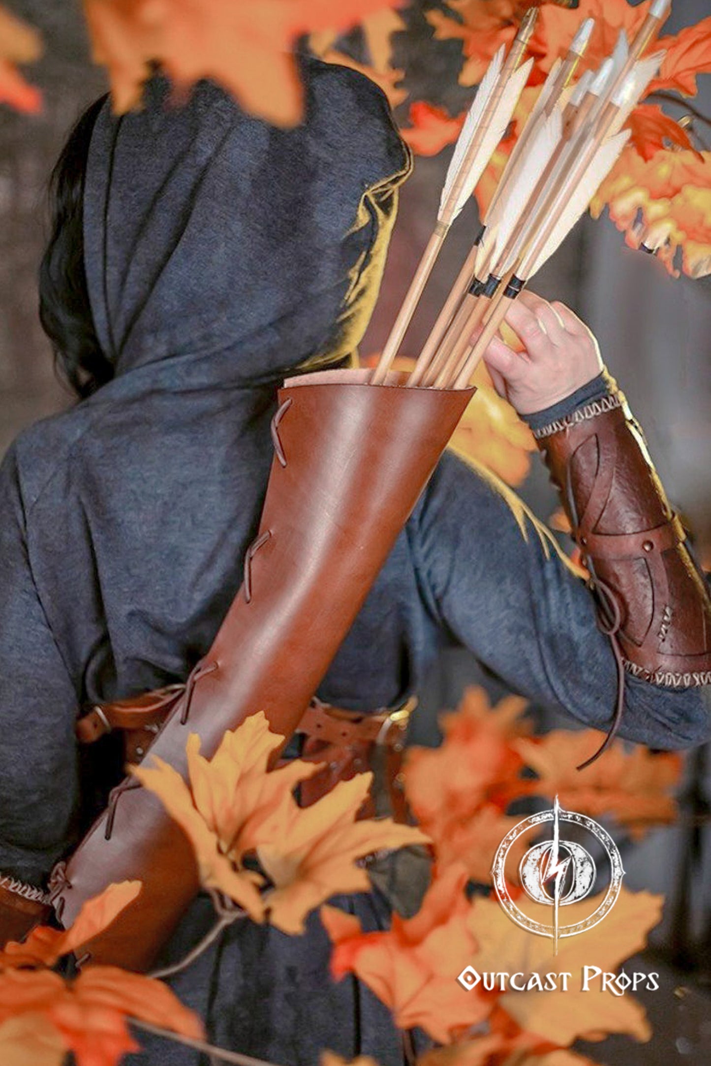 Fantasy archer drawing an arrow from a leather quiver strapped across their back. Surrounded by autumn leaves, the image evokes scenes from fantasy roleplay, perfect for a larp quiver character. The brown leather arrow quiver stands out clearly, offering an immersive touch to elf armor, cosplay or archery quiver gear. Made for roleplayers and reenactors.