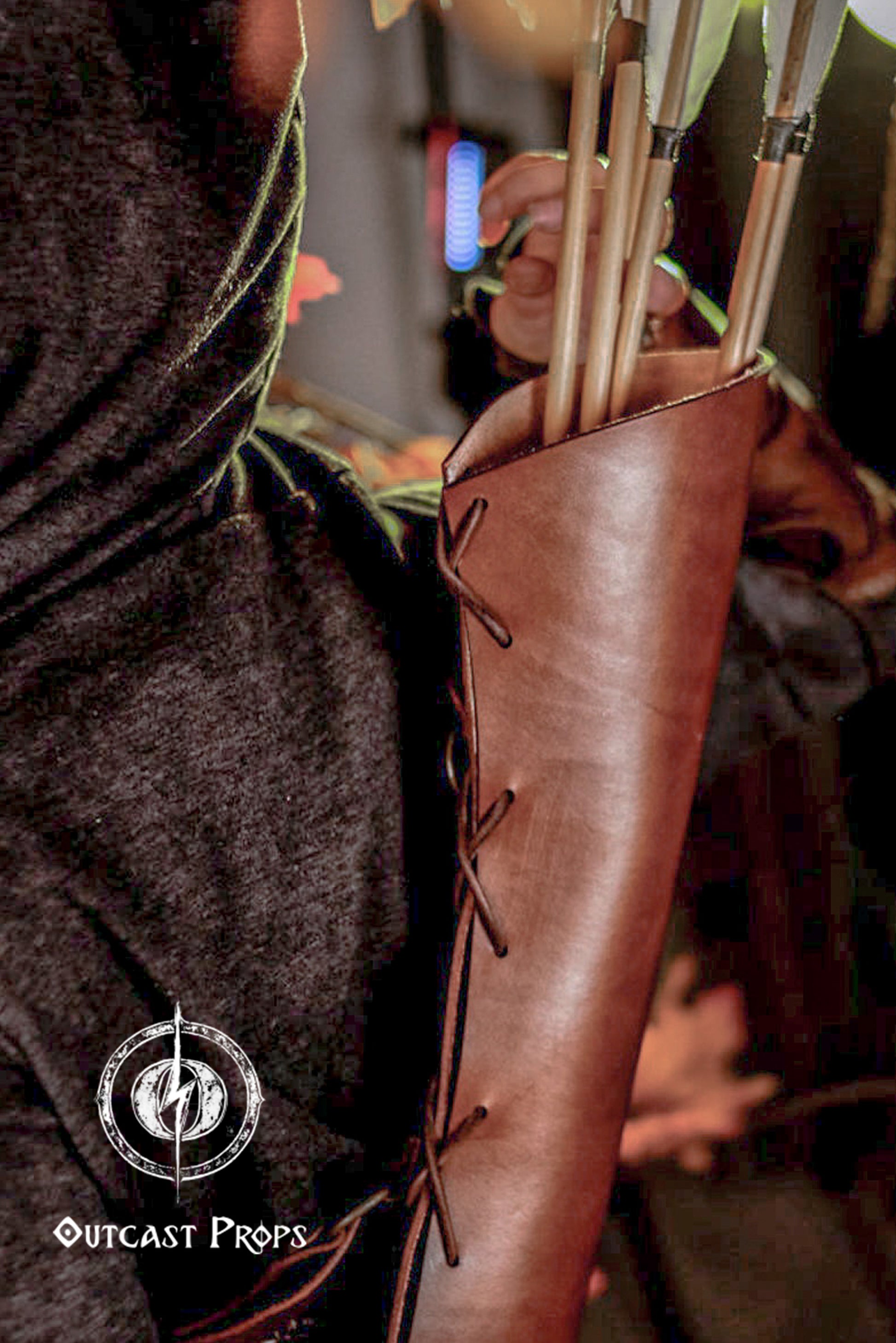 Close-up of a hand reaching into a leather quiver filled with wooden arrows. The rich leather contrasts with the dark cloak and autumn leaves, creating a cinematic shot. This archery quiver is ideal for cosplay, larp quiver action, or medieval costume. With secure lacing and clean cut, this leather arrow quiver is fantasy gear for any bow and arrow cosplay setup.