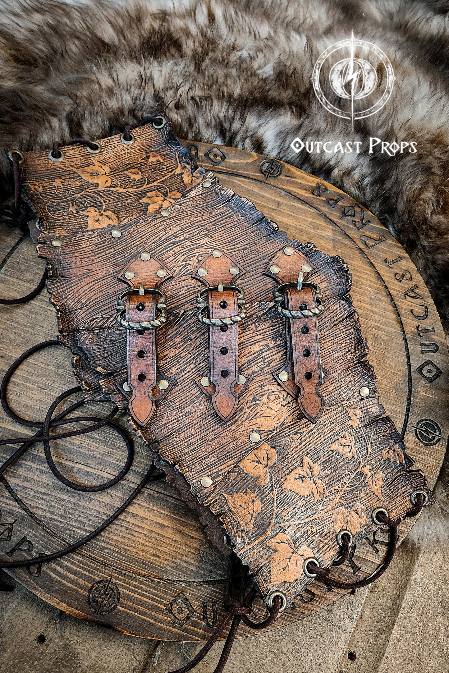 Wooden belt with leather straps on a fur background, featuring 'Outcast Props' branding. Underbust Wood Leather Corset. Herbalist corset. Druid corset. Elven Corset. Ivy Corset.