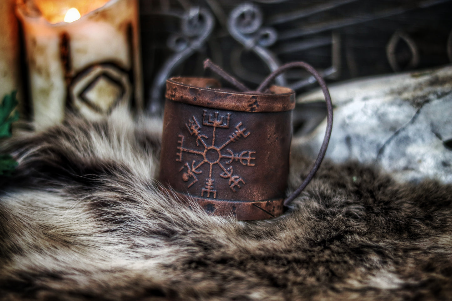 A brown leather wristband with a Viking compass design, displayed on a furry surface, featuring intricate handcrafted details. Vegvisir Leather Wristband, Galdrastafir Viking Bracelet, Icelandic way finder rune leather embossed cuff, LARP, cosplay