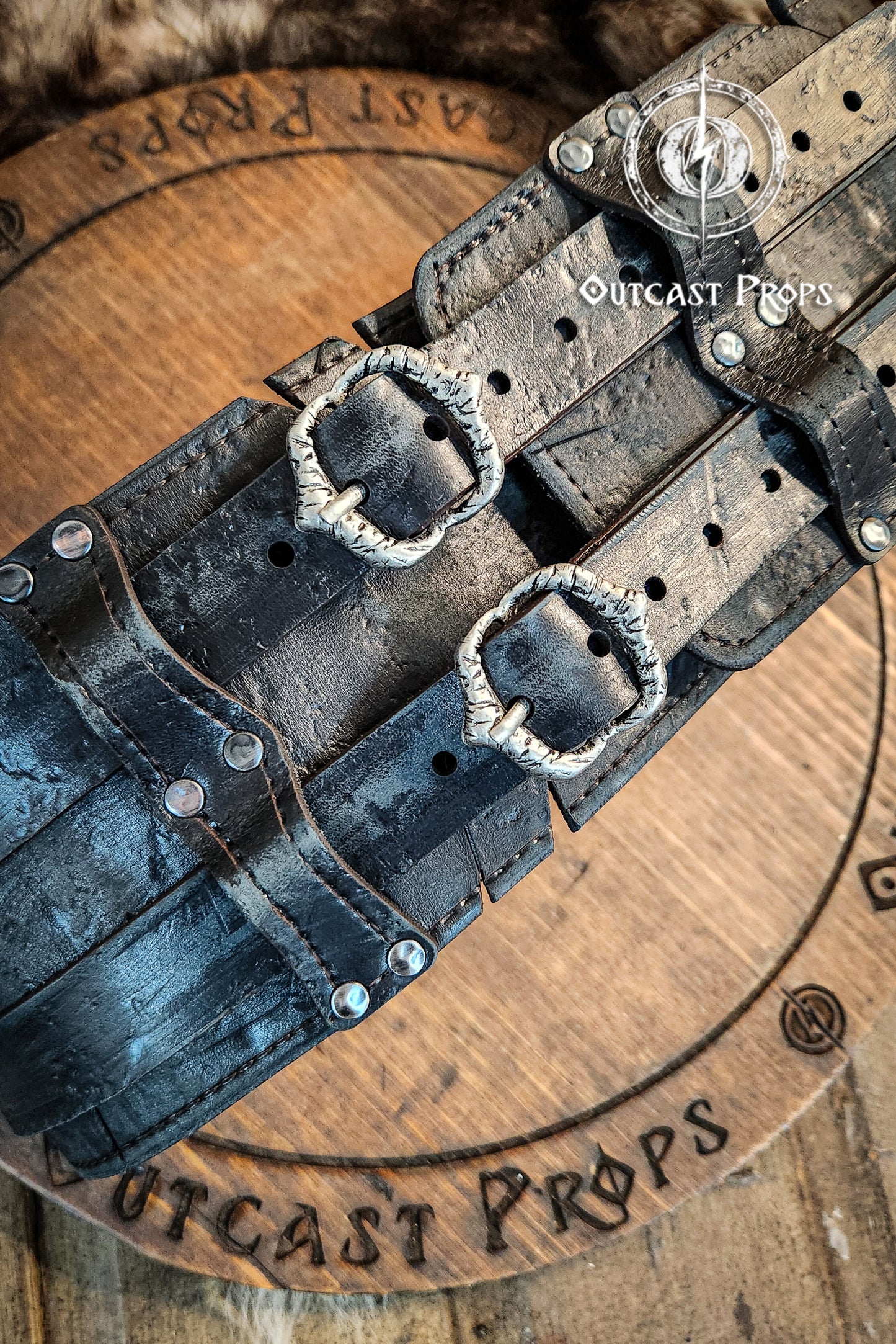 Black leather belt with silver buckles on a wooden surface with 'Outcast Props' branding. Black doble leather broadbelt with silver buckles on a wooden surface with 'Outcast Props' branding. Veteran Leather Belt. Medieval leather belt. Orc belt. Warrior belt for larp.