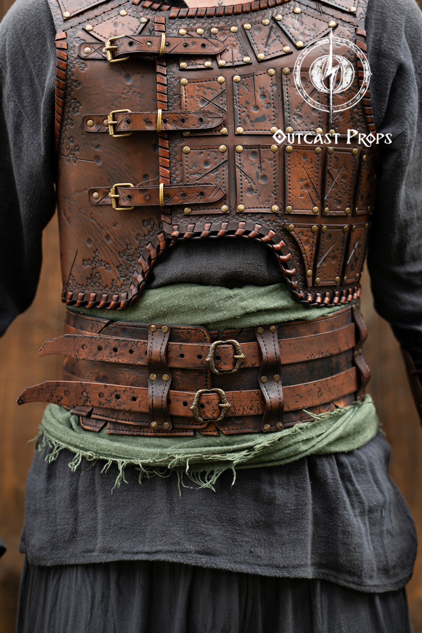 Brown leather vest with gold buckles and Outcast Props branding on a blurred background. Leather Broadbelt in brown leatrher, battle worn, aged. Veteran Leather Belt premium vegetable-tanned, worn by raiders and mercenaries