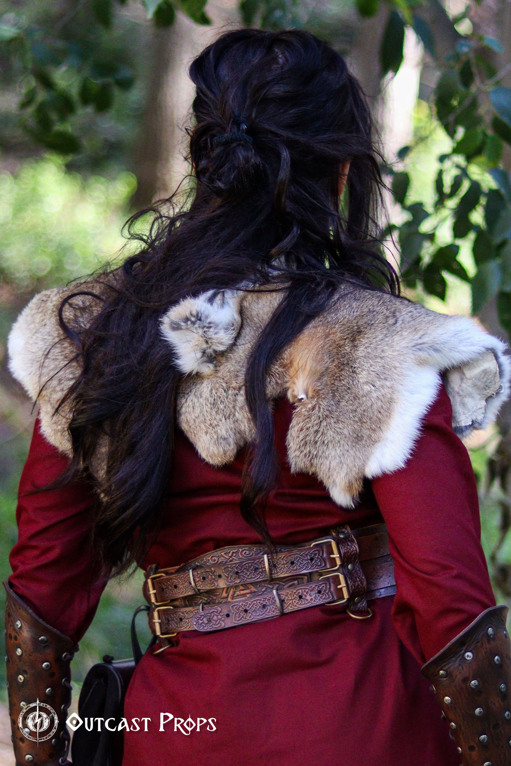 Back view of the leather celtic fantasy belt on a woman in red dress and fur mantle. The viking leather armor belt curves at the waist with detailed knotwork and sturdy brass buckles. Great for medieval warrior armor, barbarian cosplay outfit, or renfaire costume wide. SEO optimized for larp gear and fantasy accessory needs.