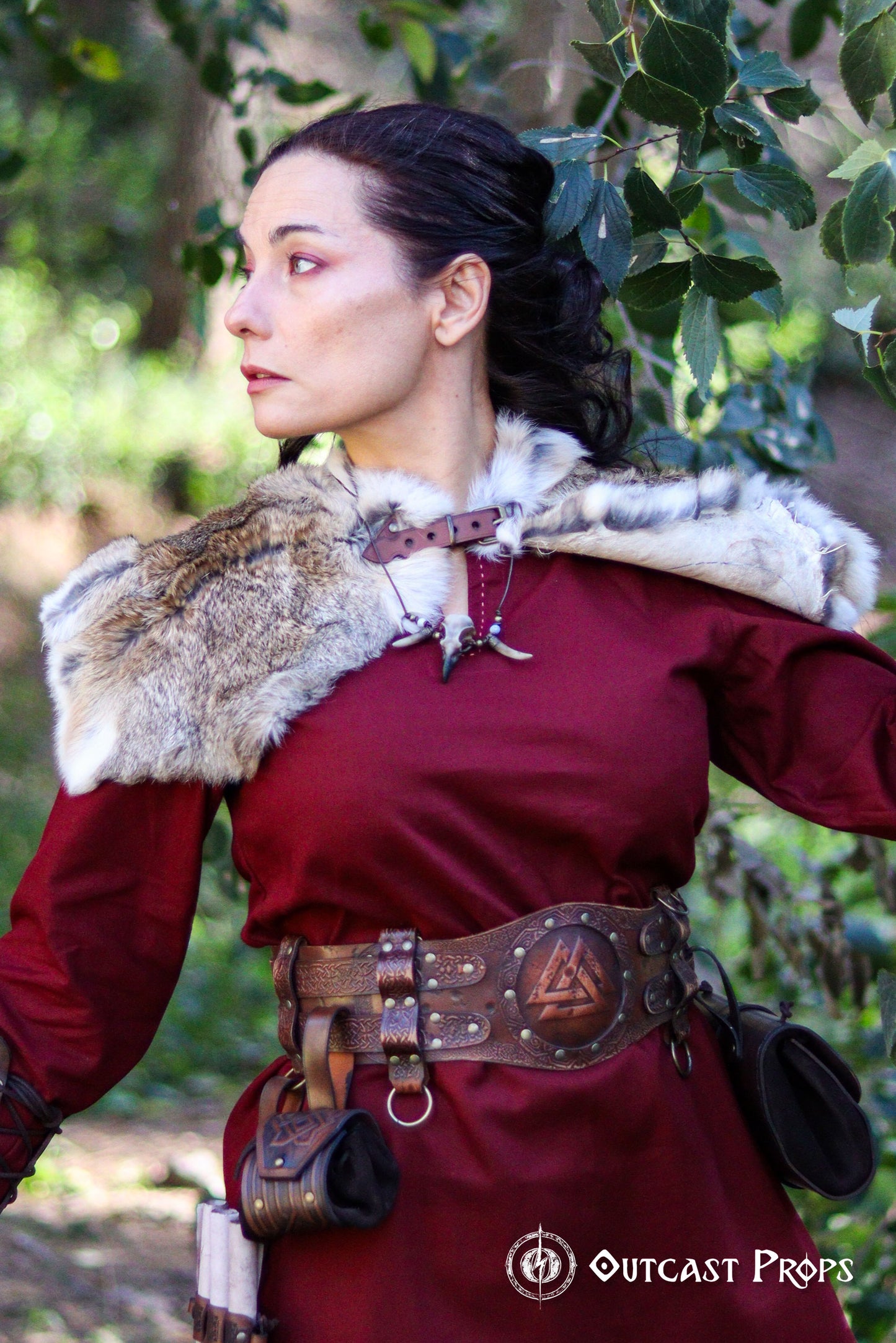 Brown viking leather armor belt on female model in red dress with fur shoulder cape. The belt shows Norse knotwork and a Valknut center, perfect for a celtic fantasy belt or renfaire costume wide. Ideal for LARP warriors or fantasy cosplay. The wide belt enhances the silhouette and secures accessories. Handmade and visually textured.