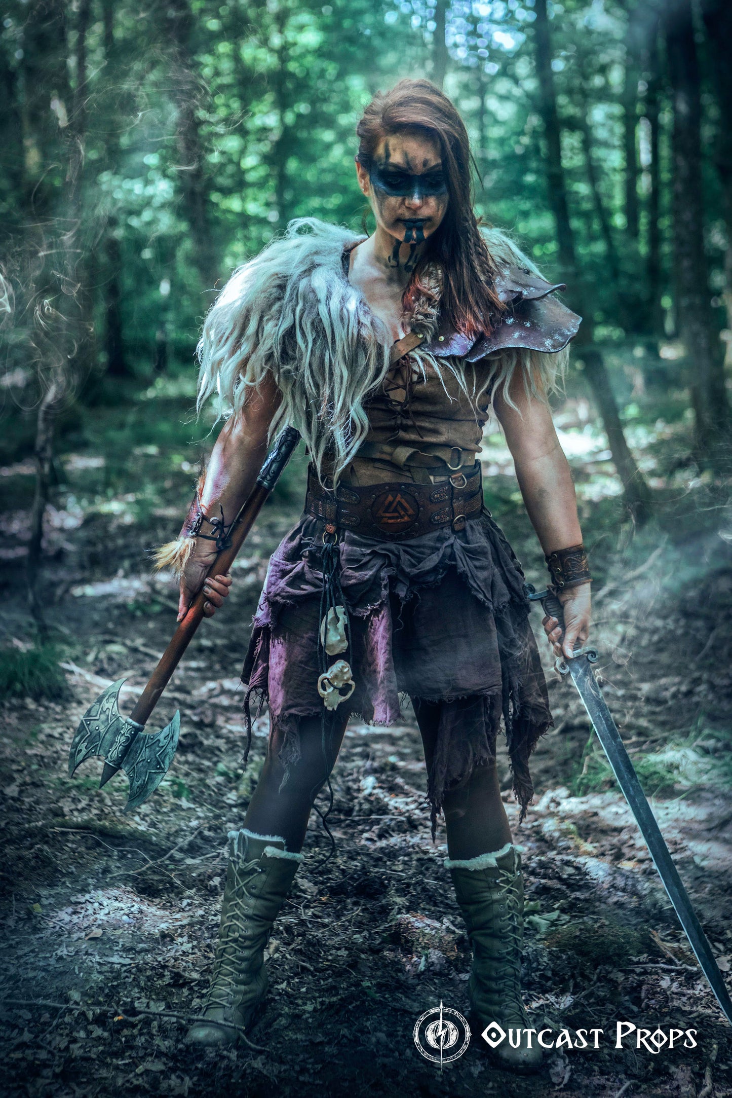 Barbarian cosplay outfit worn by a woman model showing the viking leather armor belt with Valknut design. The wide belt cinches the waist and supports pouches and gear, matching the celtic fantasy belt theme. Ideal for LARP, fantasy warrior look, or renfaire costume. The photo captures the rugged, immersive style in a dark wooden hut.