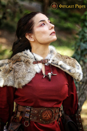 Cosplay model gazing upwards while wearing a light brown fur Viking mantle with a fantasy leather clasp. Styled with a red medieval dress and a Norse-style belt, this outfit is perfect for Viking shieldmaidens, tribal huntresses or barbarian priestesses in LARP or cosplay. Handmade with real fur and medieval aesthetics, ideal for fantasy roleplay, reenactment or immersive fairs.