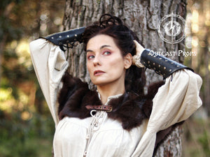 LARP model in woodland surroundings wearing a soft brown and white Viking fur mantle with leather closure. Paired with red medieval clothing and horned skull necklace, this handmade shoulder cape is perfect for fantasy priestess cosplay, barbarian characters, or Celtic-inspired costumes. Great for Renaissance fairs, Viking reenactments or tribal LARP roles. Warm and immersive design.