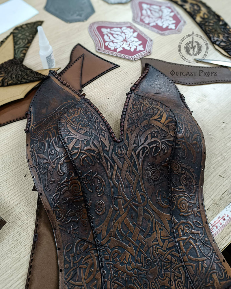 Viking-inspired women's leather armor front panel with interlacing knotwork on the workshop bench