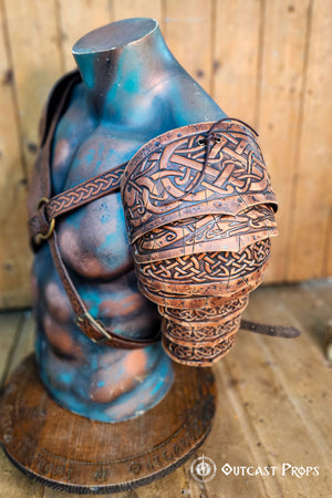 Side view of Sedrik Viking leather shoulder armor, highlighting engraved Celtic knots on overlapping brown leather plates. Armor worn on a muscular mannequin torso, with adjustable leather straps crossing the chest, metal ring centerpiece, and a wooden background. Perfect for Viking cosplay, Celtic LARP costume, Norse warrior outfit, fantasy roleplay armor, medieval festival gear, premium handcrafted leather pauldrons with cinematic weathering effects.