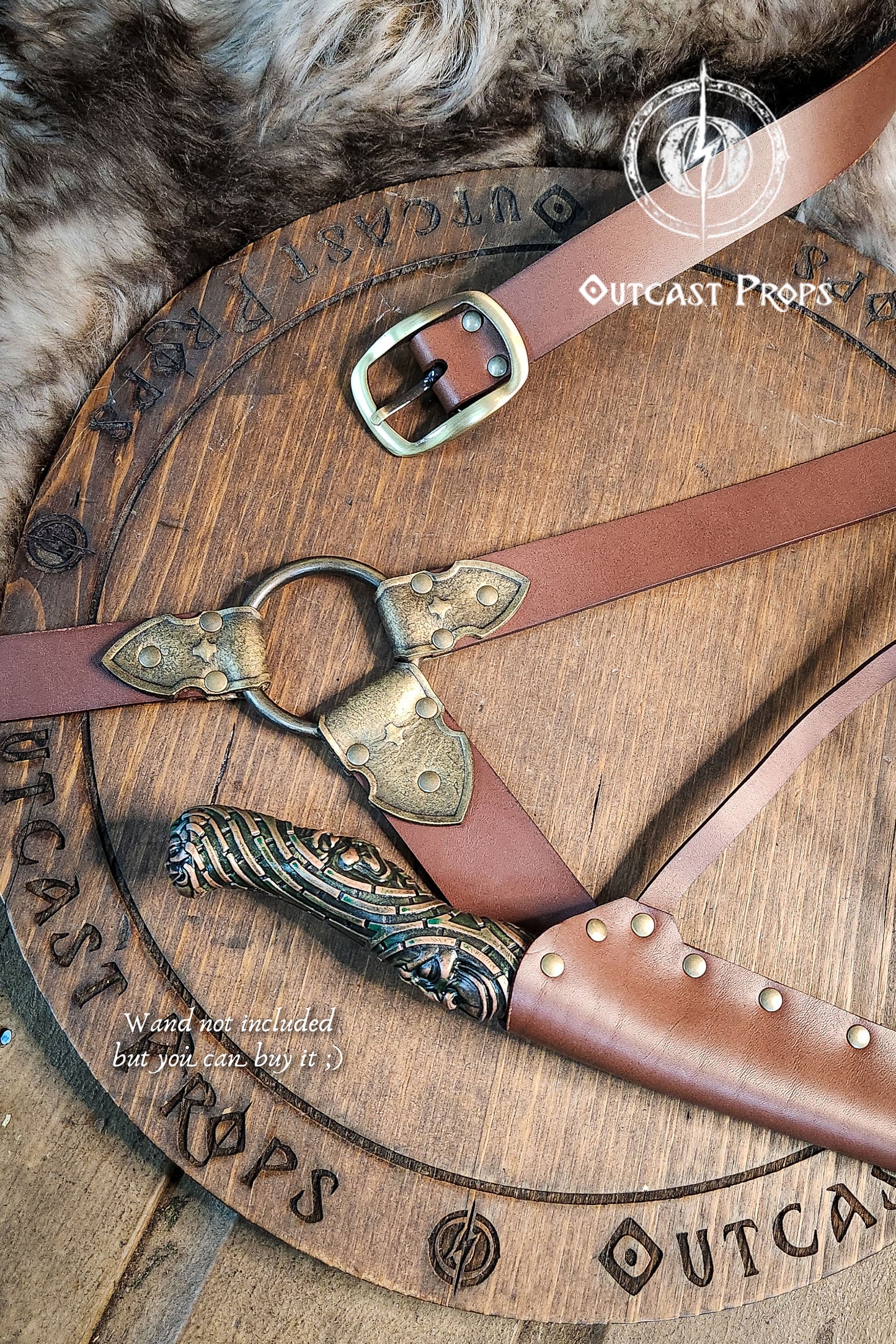 Brown leather belts with decorative buckles on a wooden surface with 'Outcast Props' branding.