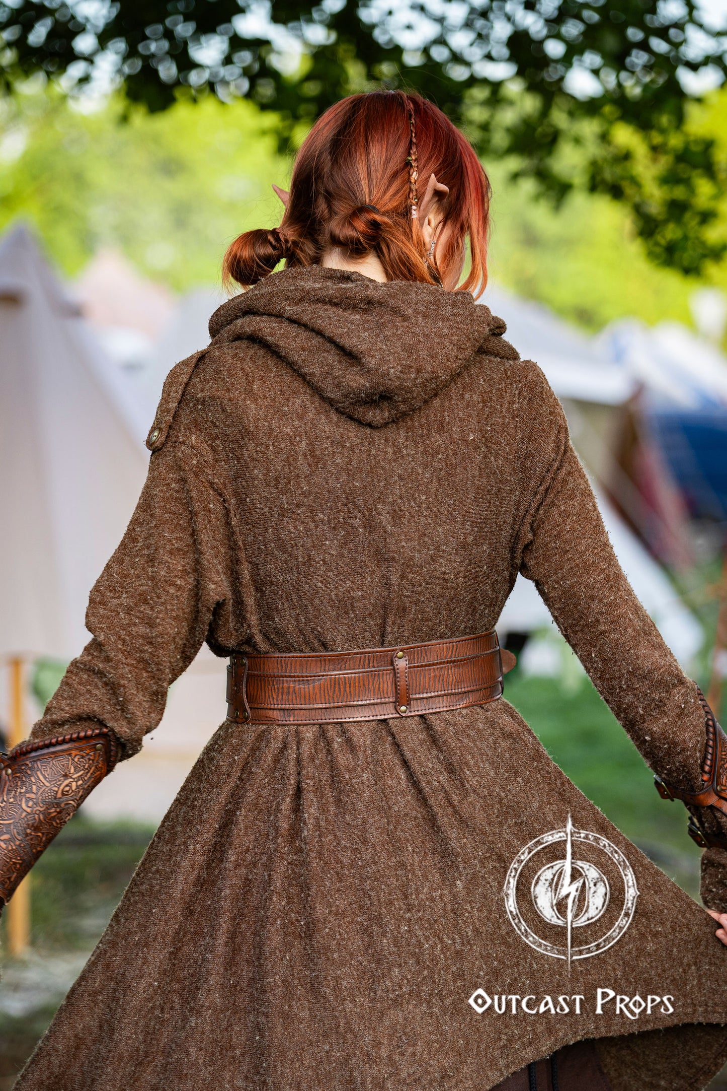 Person wearing a brown coat with a hood, standing outdoors with tents in the background. Celtic knot leather belt silver buckle larp belt for ren fair fantasy costume celtic belt unisex leather belt for renaissance outfit