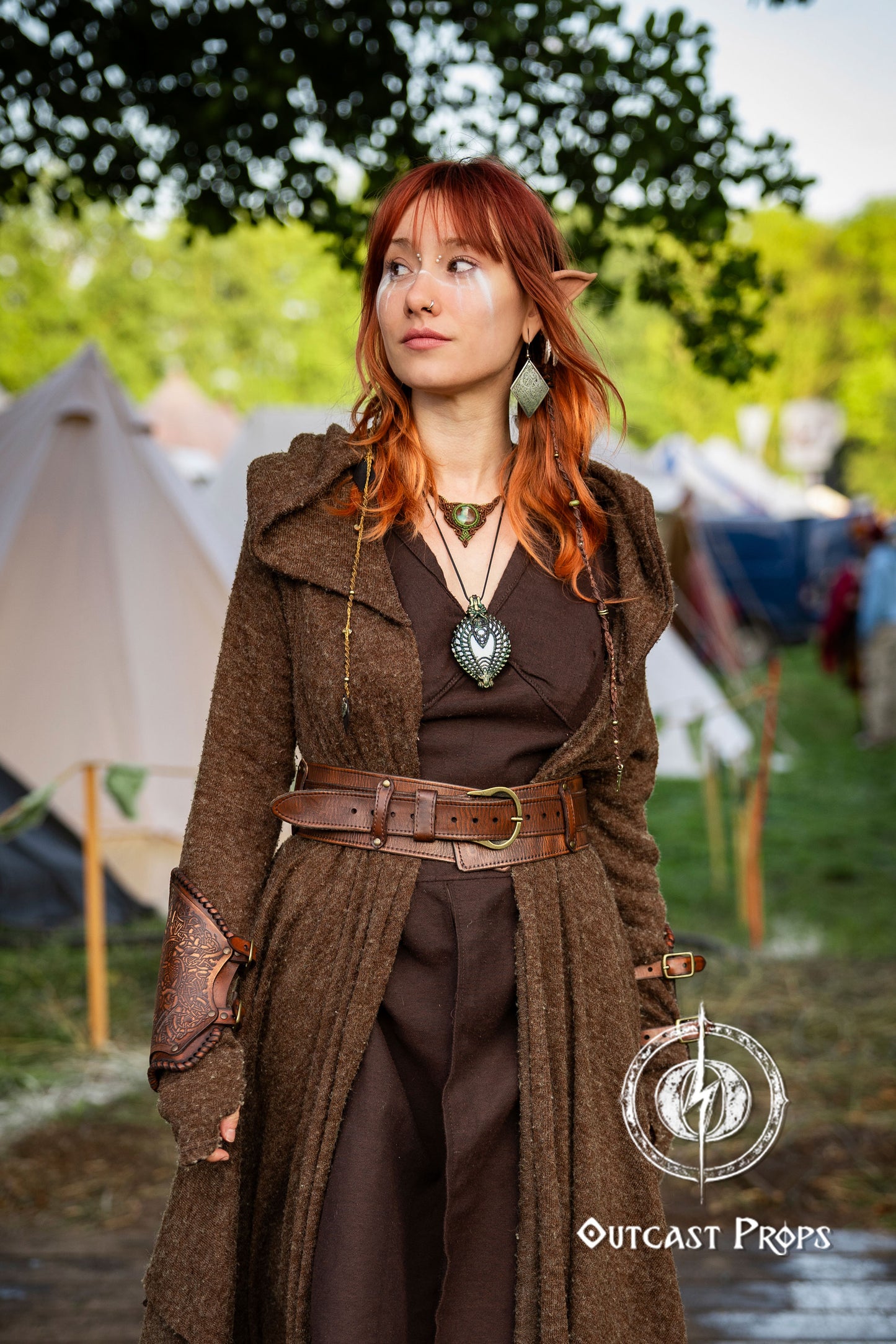 Person in a brown coat with a belt and leather pouches standing outdoors with tents in the background. Celtic knot leather belt silver buckle larp belt for ren fair fantasy costume celtic belt unisex leather belt for renaissance outfit