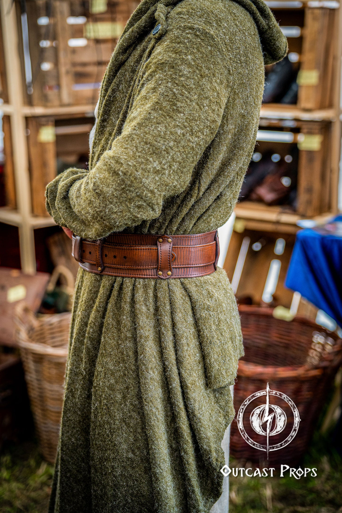 Person wearing a green robe with a brown belt in a rustic setting, with 'Outcast Props' branding. Celtic knot leather belt silver buckle larp belt for ren fair fantasy costume celtic belt unisex leather belt for renaissance outfit