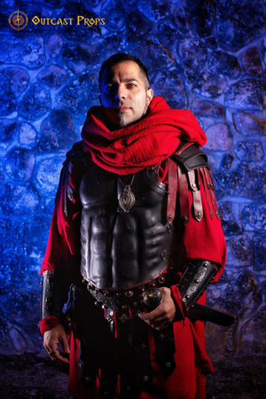 Cosplayer wearing black Roman gladiator leather cuirass with red cloak and accessories, posed under blue light against a stone wall. This muscular Roman chest armor is ideal for historical LARP, fantasy warriors, or Spartacus reenactment. High contrast between costume and background supports screen readers in visual storytelling. Crafted from premium leather and aged for epic realism.