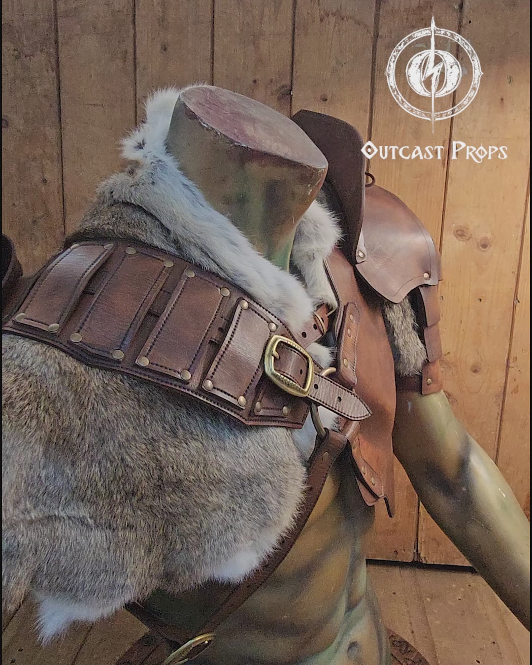 Leather barbarian armor set displayed on a muscular torso mannequin, featuring shoulder pauldrons, a chest harness, and thick grey rabbit fur mantle. Made from vegetable-tanned leather in aged brown tone, with weathered straps and metal buckles. Ideal for LARP, Viking cosplay or post-apocalyptic costumes. The fur and armor layers create a battle-worn barbarian look, full of texture and realism.