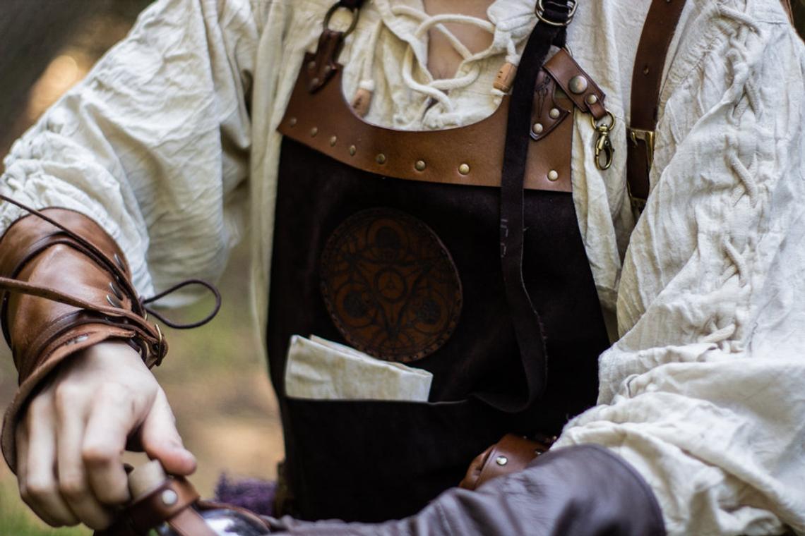 A person wearing a brown leather apron with pockets and a potion holder with glass bottles. Leather Apron, larp Alchemy steampunk crazy scientist mechanics, engineers. With accesories and pockets perfect for Barber