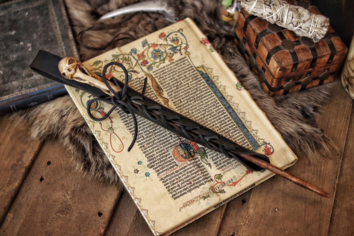 A close-up image of a brown wand holster with a leather strap and lace detail, displayed on an open book with a decorative background. Magic Wand Leather Holster Laced & Aged, perfect sheath for wizzards to hang from your belt, witch wand belt seath cosplay LARP