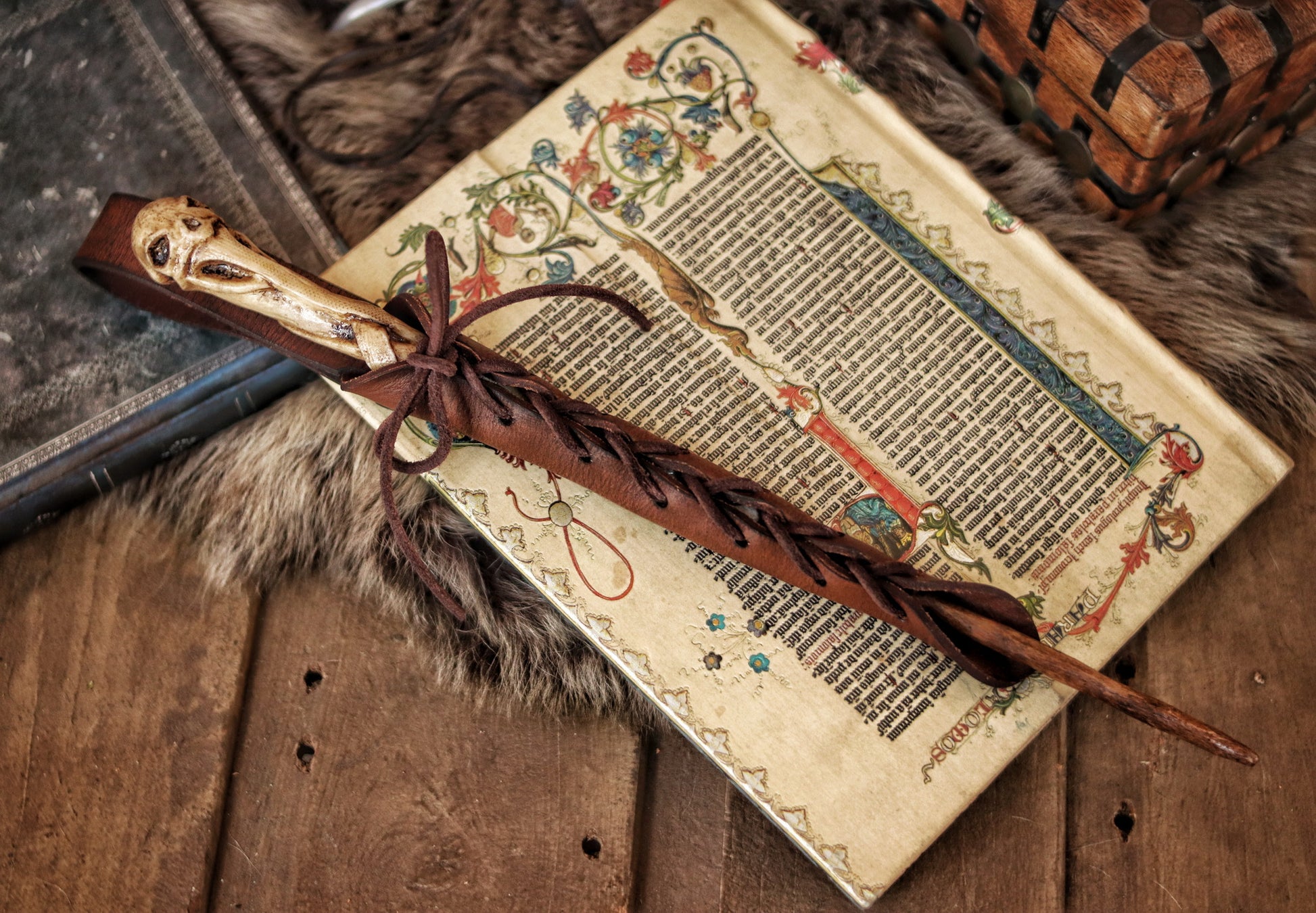 A close-up image of a brown wand holster with a leather strap and lace detail, displayed on an open book with a decorative background. Magic Wand Leather Holster Laced & Aged, perfect sheath for wizzards to hang from your belt, witch wand belt seath cosplay LARP