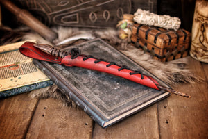 A close-up image of a brown wand holster with a leather strap and lace detail, displayed on an open book with a decorative background. Magic Wand Leather Holster Laced & Aged, perfect sheath for wizzards to hang from your belt, witch wand belt seath cosplay LARP