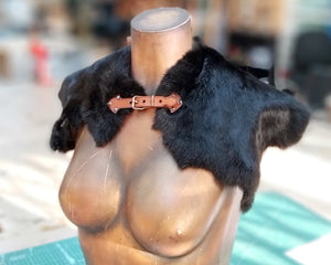 Black Viking fur mantle displayed on a female torso mannequin. The piece features soft natural fur with a handcrafted brown leather clasp at the front. Ideal for barbarian warrior costumes, tribal LARP outfits, or medieval druid cosplay. A rugged, fantasy-inspired shoulder cape perfect for Renaissance fairs, Nordic reenactments, or historical roleplay events. Handmade accessory for cold-weather characters.