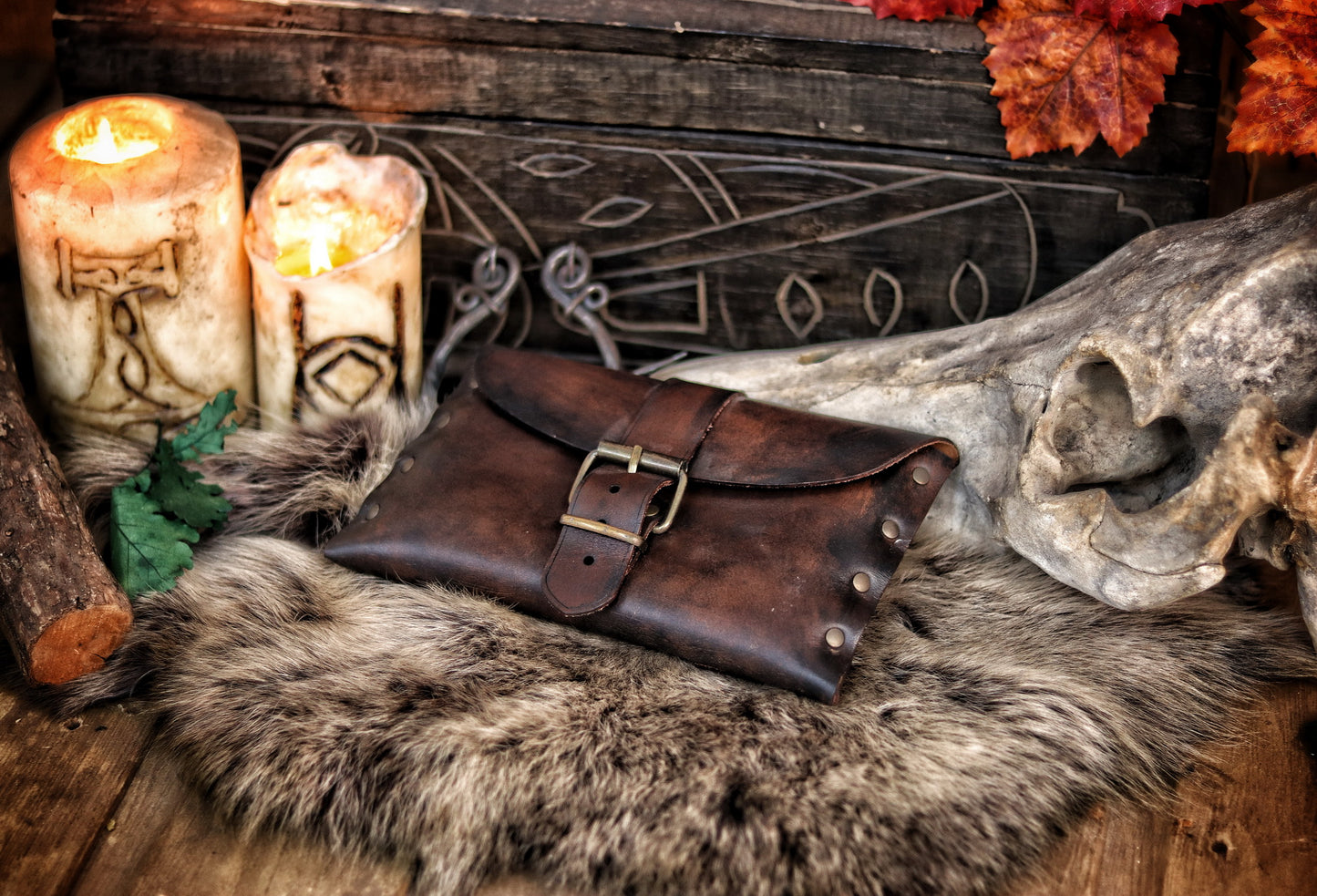 Dark brown fantasy leather pouch resting on fur beside engraved candles and skull. A rustic LARP belt pouch for medieval or Viking reenactment, featuring brass buckle and side rivets. Handmade leather bag for costume or practical use. Scene evokes Nordic or druidic vibe. Alt text designed for SEO and visually descriptive for accessibility.