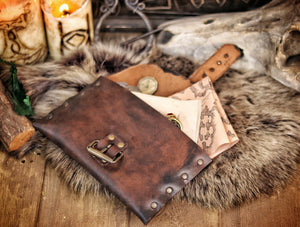 Open medieval leather pouch with brass buckle, revealing fantasy maps and scrolls inside. Ideal LARP document pouch or Renaissance fair accessory. Crafted from distressed brown leather, lying on fur with candlelight. Great for scribes, messengers, or immersive character props. Long tail optimized for handmade leather pouch with documents.