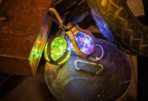 Two illuminated steampunk potion bottles with vibrant LED lights, leather harnesses, and rustic metal accents. Designed for cosplay, LARP, or sci-fi events. PET plastic bottles with secure battery compartments using LR44 alkaline cells, easy to attach to belts.
