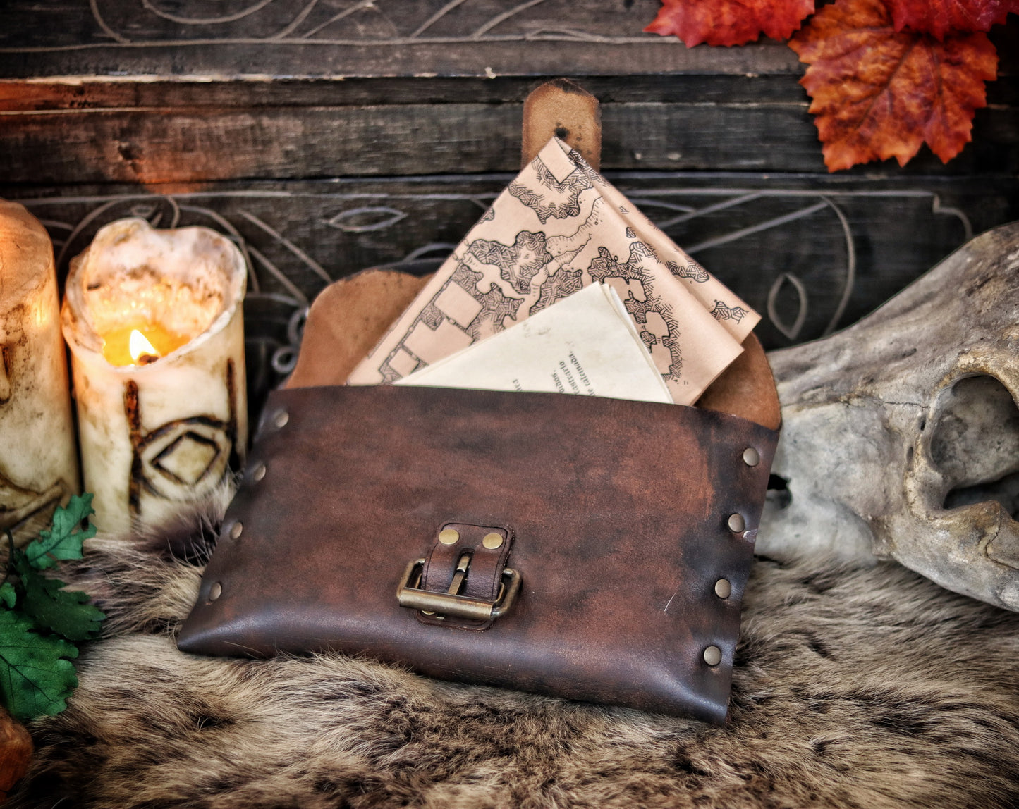 Open medieval leather pouch with brass buckle, revealing fantasy maps and scrolls inside. Ideal LARP document pouch or Renaissance fair accessory. Crafted from distressed brown leather, lying on fur with candlelight. Great for scribes, messengers, or immersive character props. Long tail optimized for handmade leather pouch with documents.