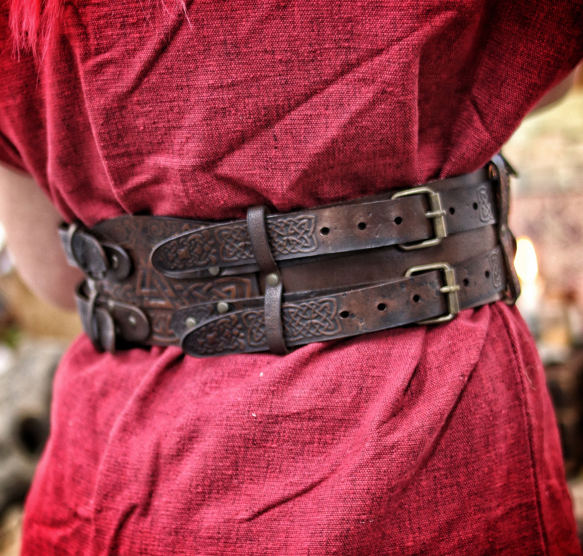 Back view of the leather celtic fantasy belt on a woman in red dress and fur mantle. The viking leather armor belt curves at the waist with detailed knotwork and sturdy brass buckles. Great for medieval warrior armor, barbarian cosplay outfit, or renfaire costume wide. SEO optimized for larp gear and fantasy accessory needs.