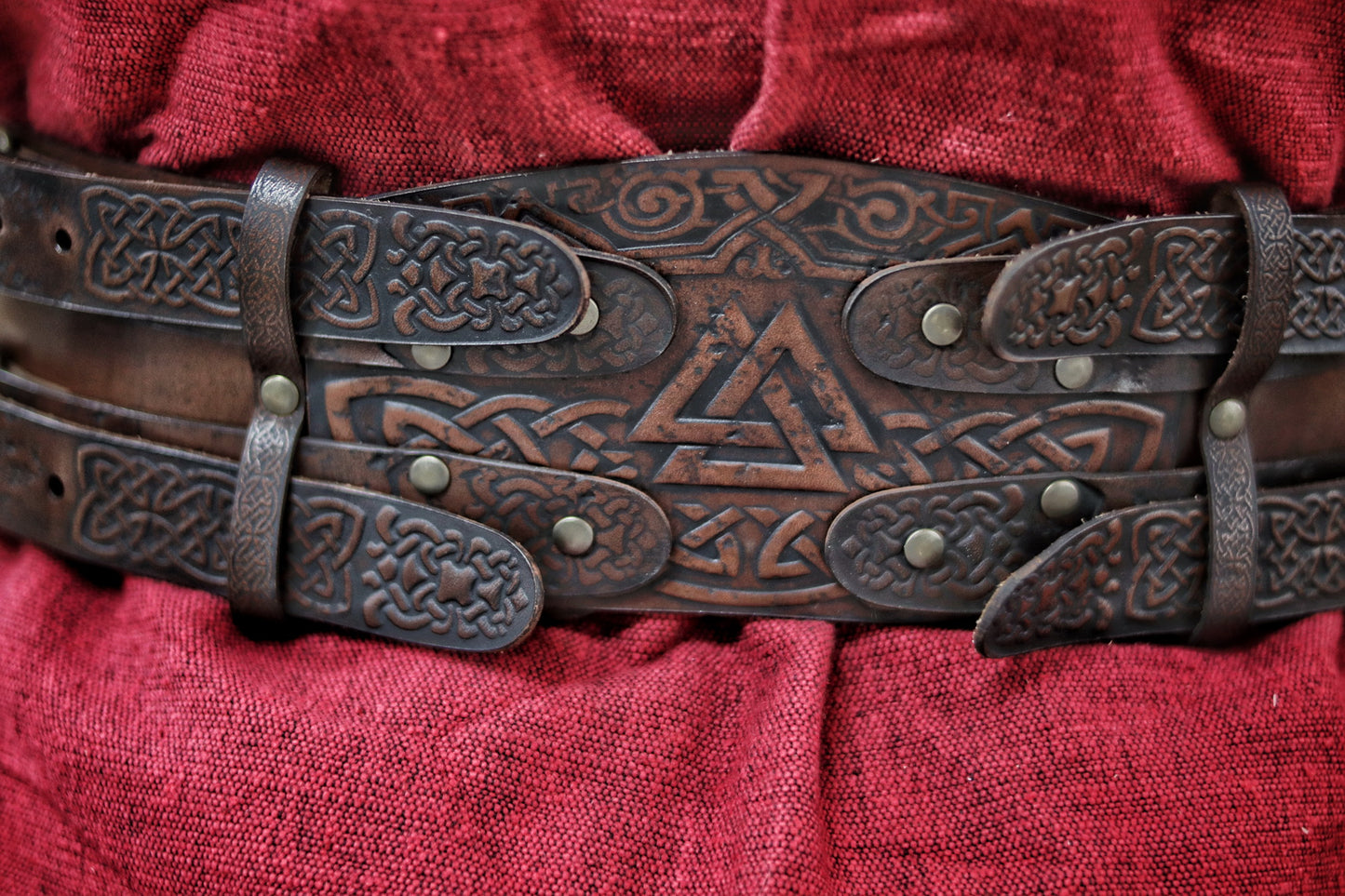 Back view of the leather celtic fantasy belt on a woman in red dress and fur mantle. The viking leather armor belt curves at the waist with detailed knotwork and sturdy brass buckles. Great for medieval warrior armor, barbarian cosplay outfit, or renfaire costume wide. SEO optimized for larp gear and fantasy accessory needs.