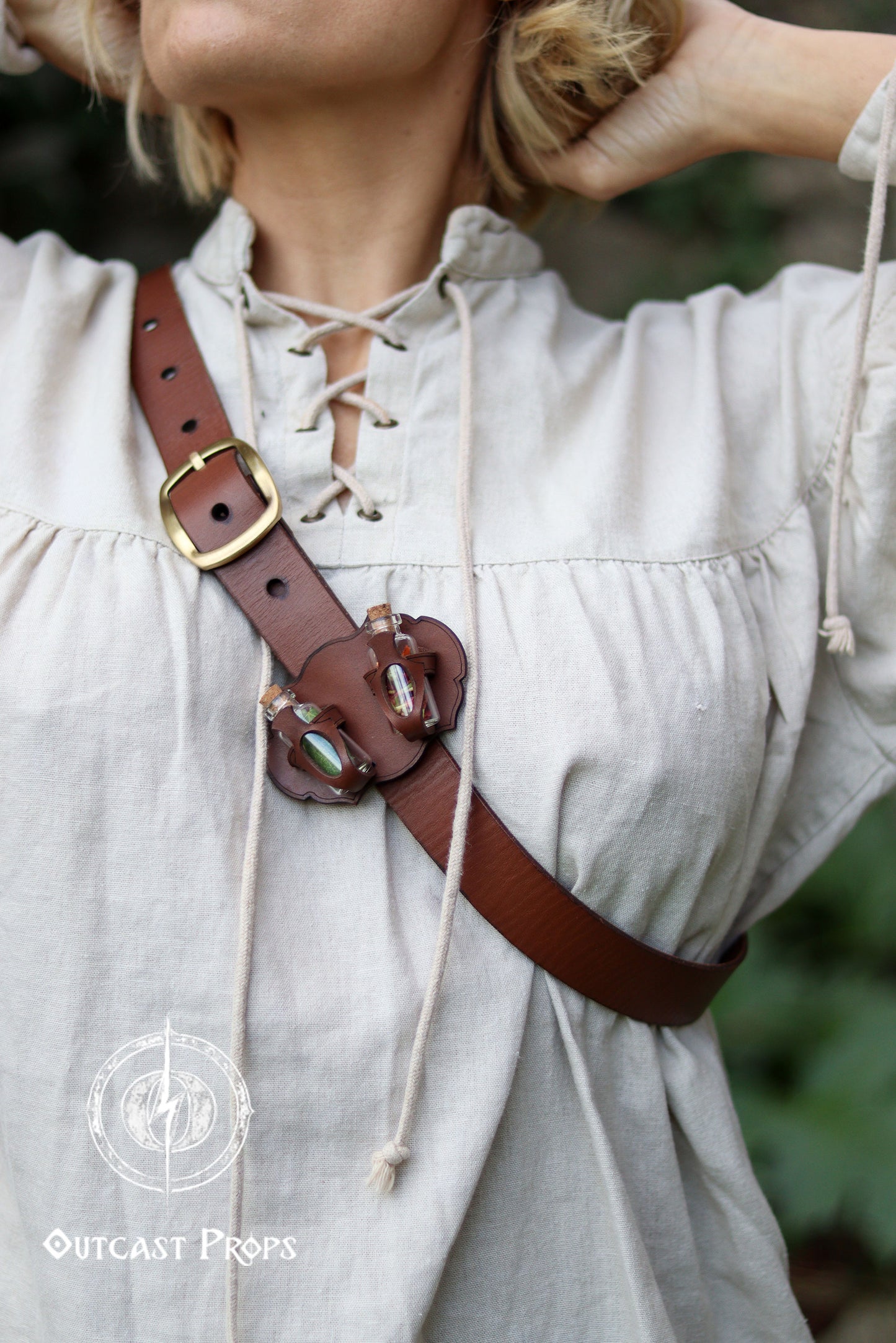 Person wearing a brown leather belt with a gold buckle on a light-colored outfit. Belt Potion holder for two small bottles. Made of leather for adventurers, steampunk, alchemist, healers, cosplay or just to keep spices
