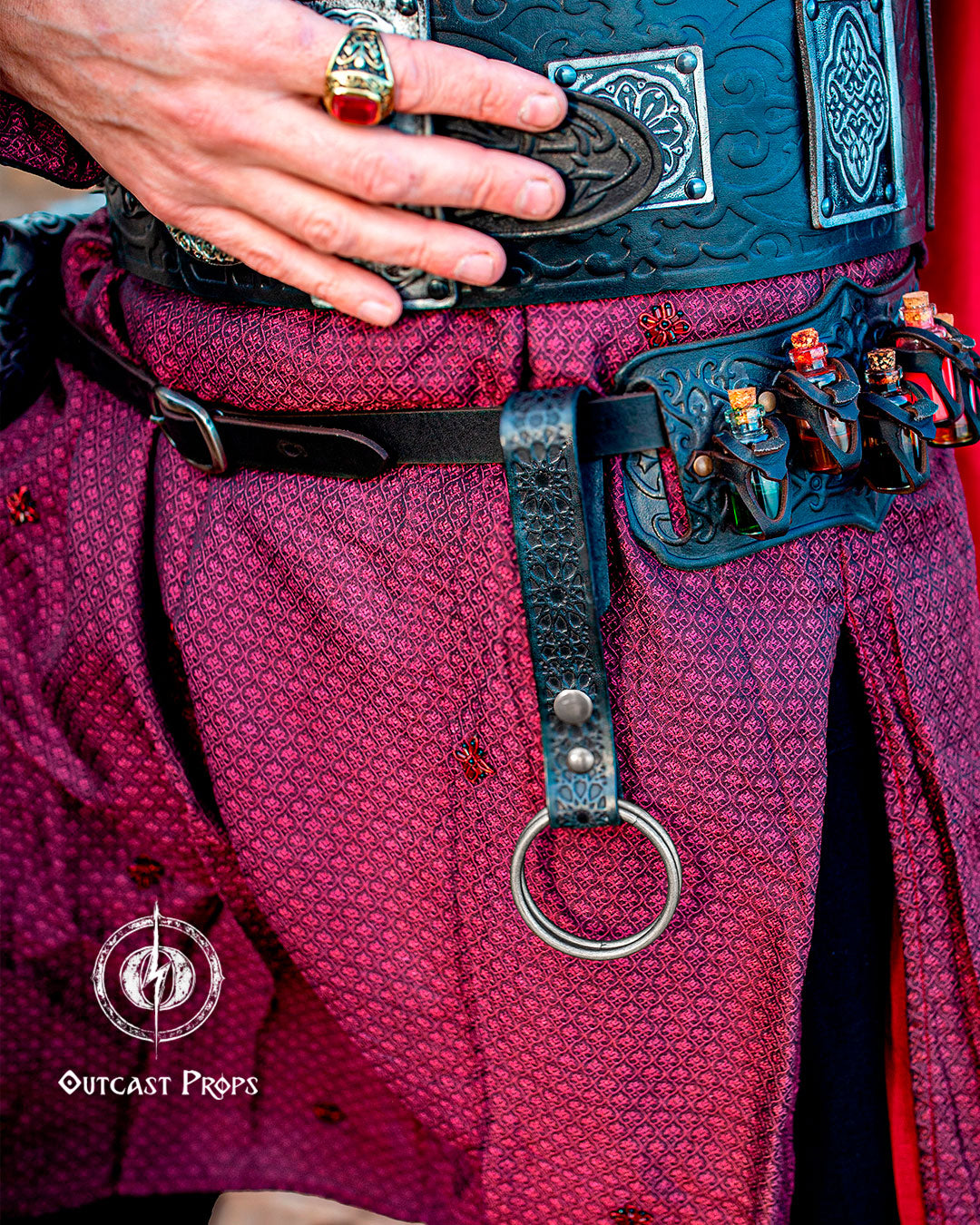 Close-up of a person wearing a detailed belt with decorative elements, likely from a costume or prop, with 'Outcast Props' branding. 20 Plain leather belt