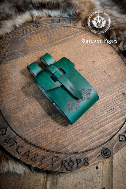 Green leather pouch on a wooden surface with 'Outcast Props' branding. Leather Vial Case for 3 plastic vials. Adventurers, steampunk, alchemist, healers, cosplay or just to keep spices