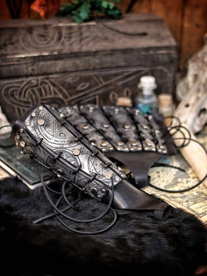 Silver leather bracer for LARP and fantasy cosplay, engraved with alchemical symbols and mystical geometry. Decorated with metal studs and polished beads for a gothic warlock or dark wizard look. Handmade from vegetable-tanned Spanish leather, adjustable and resistant. Perfect for witches, ritualists, or demon hunters in immersive fantasy roleplay.