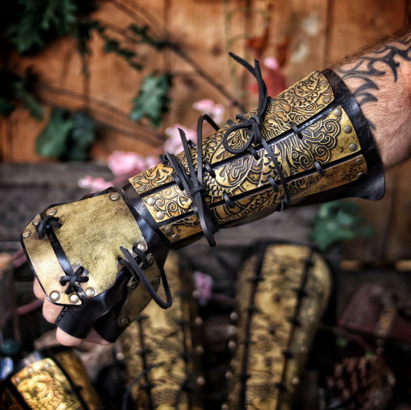 Hand wearing a full samurai bracer and handplate with golden dragon engraving, perfect for fantasy warriors or samurai larp costumes. Made from vegetable-tanned leather, stitched and aged by hand. Ideal for cosplay armor, dragon samurai outfits, or noble martial characters in Eastern-inspired RPGs. The articulated finger protection adds immersive detail. Rugged, flexible, and rich in texture. For costume use only.