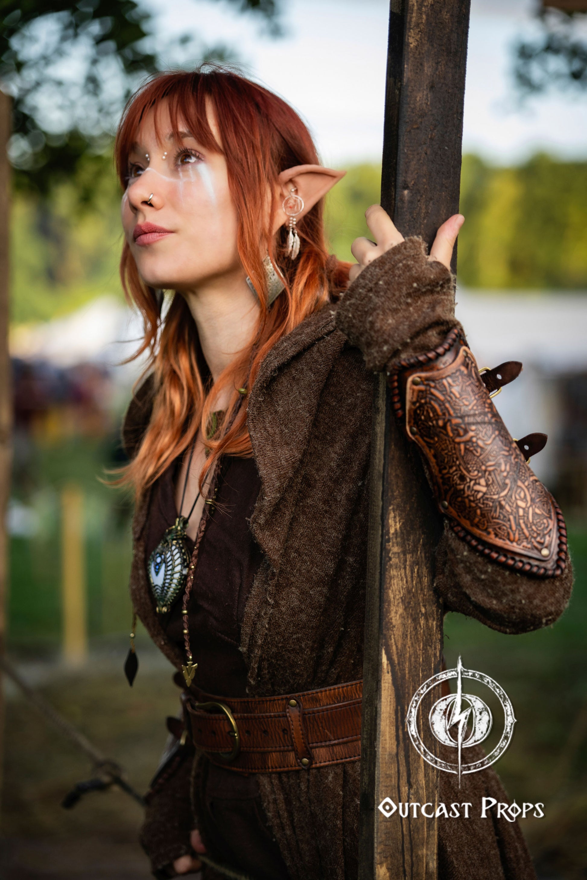 Person in fantasy costume holding a staff with 'Outcast Props' logo. Viking Leather Bracers with Norse Knot Engraving for LARP Cosplay Medieval Fantasy Roleplay Handmade Armor Custom Gear for Men or Women