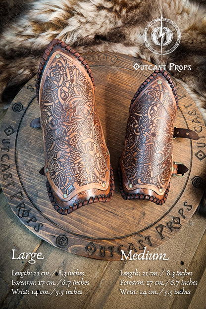 Pair of leather gauntlets with intricate designs on a wooden board, branded 'Outcast Props'. Viking Leather Bracers with Norse Knot Engraving for LARP Cosplay Medieval Fantasy Roleplay Handmade Armor Custom Gear for Men or Women