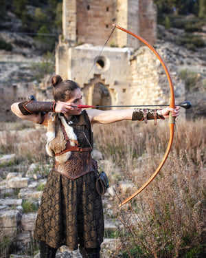A person in costume aiming a bow and arrow, wearing a Viking leather bracer. Viking Leather Bracers with Norse Knot Engraving for LARP Cosplay Medieval Fantasy Roleplay Handmade Armor Custom Gear for Men or Women