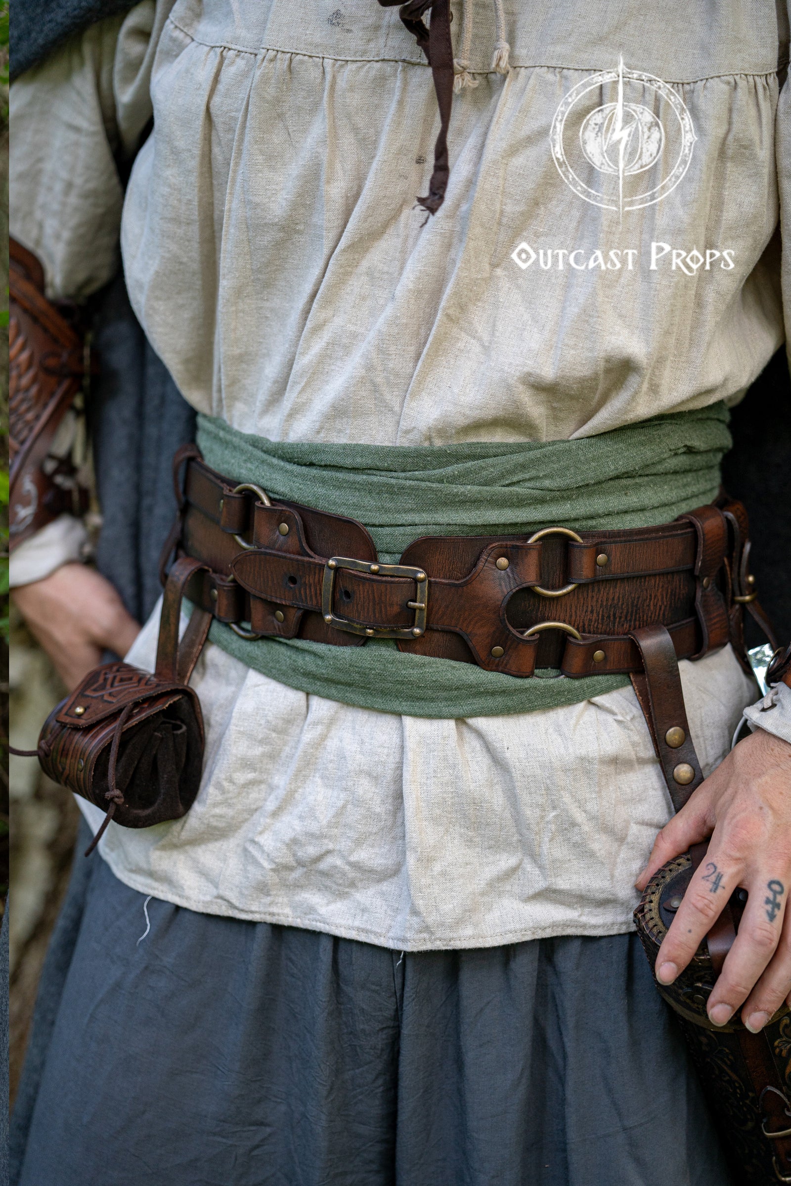 Person wearing historical clothing with a belt and pouches, featuring 'Outcast Props' logo.