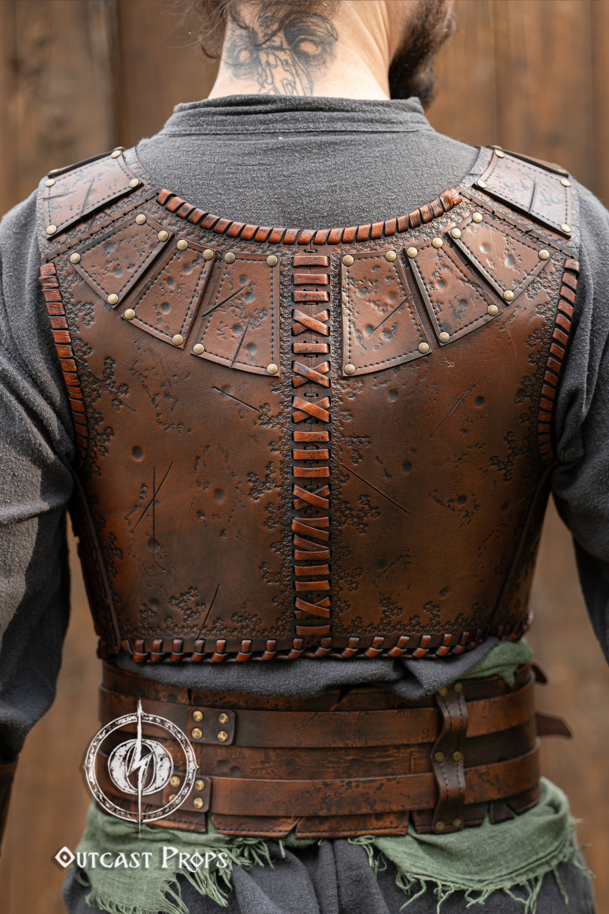 Back view of a barbarian leather armor showcasing embossed battle textures and vertical cross-stitch lacing. The segmented shoulder panels and fitted cut highlight mobility and comfort. Made from high-quality vegetable-tanned leather, this armor piece is ideal for fantasy LARP outfits, viking warriors or roleplay costumes. Features aged painting and artisanal craftsmanship by Outcast Props. Viking Studded Leather Armor Chest Armor for Men LARP Armor Witcher Leather Armour Medieval Leather Armor Cosplay