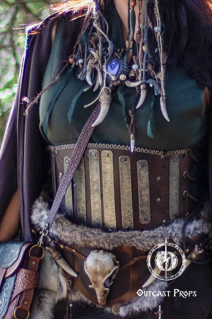 Close-up of a detailed costume with leather straps and decorative elements, featuring 'Outcast Props' logo. Barbarian Leather armor woman, larp armor woman viking piece woman post apocalyptic cosplay