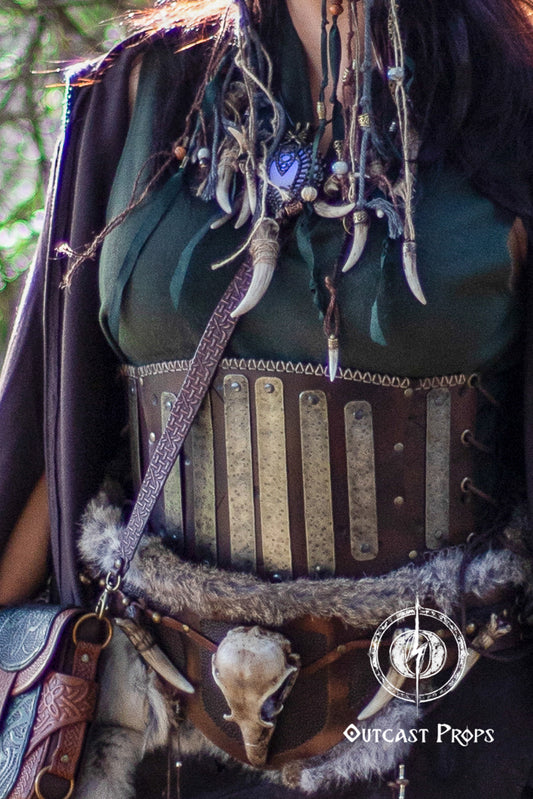 Close-up of a detailed costume with leather straps and decorative elements, featuring 'Outcast Props' logo. Barbarian Leather armor woman, larp armor woman viking piece woman post apocalyptic cosplay