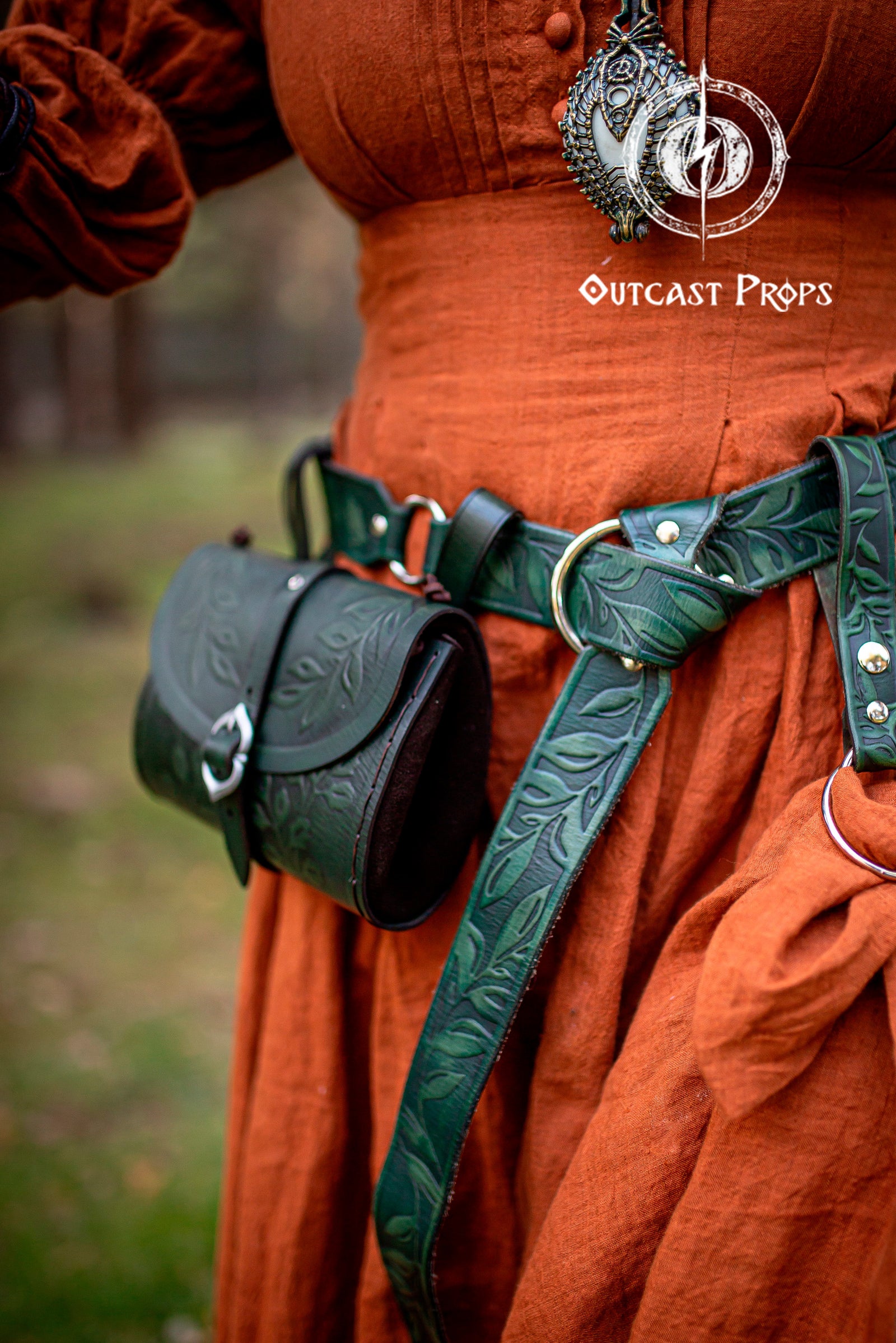 Handcrafted floral leather hip bag pouch shown as part of a renaissance faire costume, made from full grain vegetable-tanned leather with embossed floral motifs and aged brown finish. The leather bag hangs securely from the belt and closes with an easy-to-use buckle, combining historical aesthetics with everyday practicality. Designed for LARP, medieval cosplay and fantasy events, this floral hip bag can hold modern essentials like keys, phone or small notebook while maintaining an authentic medieval look e