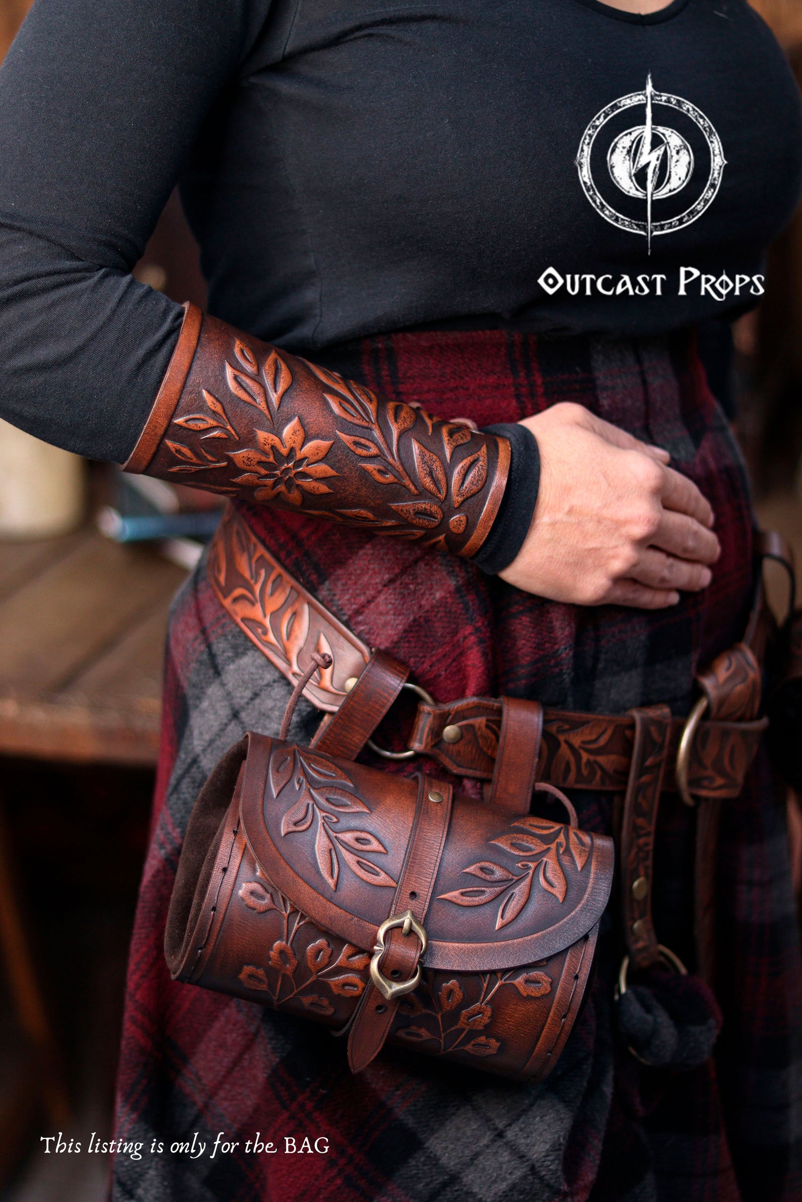 Handcrafted floral leather hip bag pouch shown as part of a renaissance faire costume, made from full grain vegetable-tanned leather with embossed floral motifs and aged brown finish. The leather bag hangs securely from the belt and closes with an easy-to-use buckle, combining historical aesthetics with everyday practicality. Designed for LARP, medieval cosplay and fantasy events, this floral hip bag can hold modern essentials like keys, phone or small notebook while maintaining an authentic medieval look e